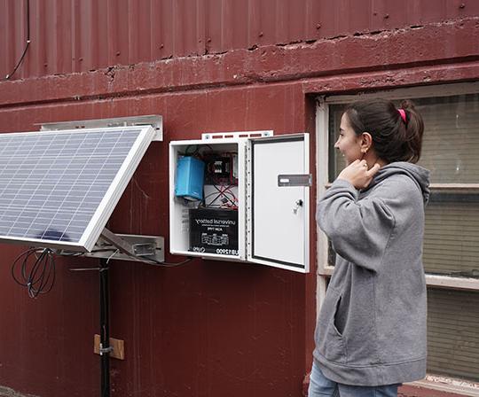 棕色头发的年轻女子指着太阳能电池板